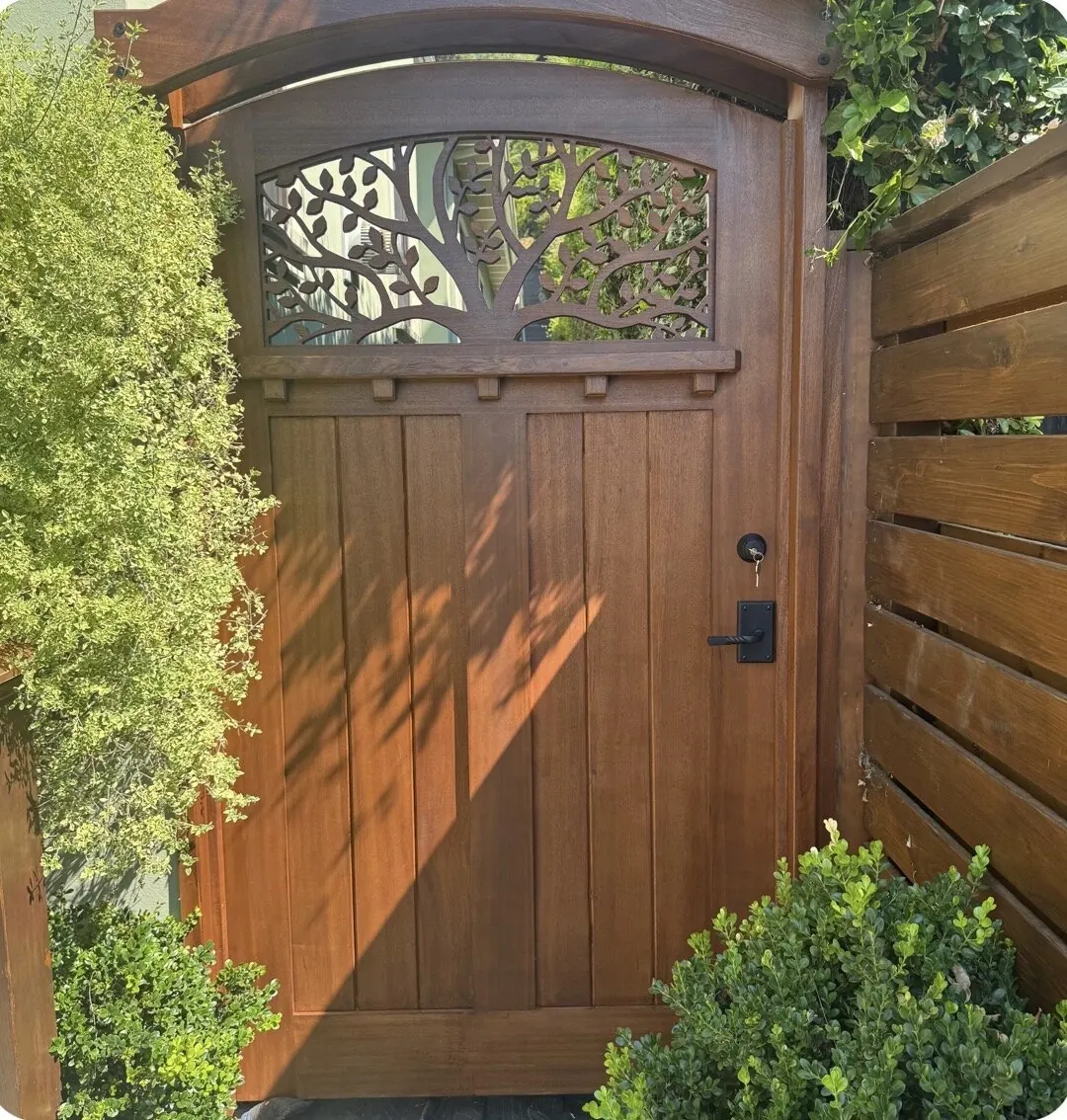 Arched mahogany craftsman gate with carved tree-of-life cutout transom and key lever lock