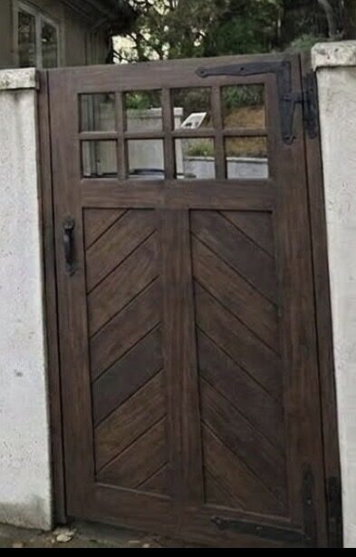 Dark stained chevron pattern craftsman side gate with divided light transom and iron strap hinge
