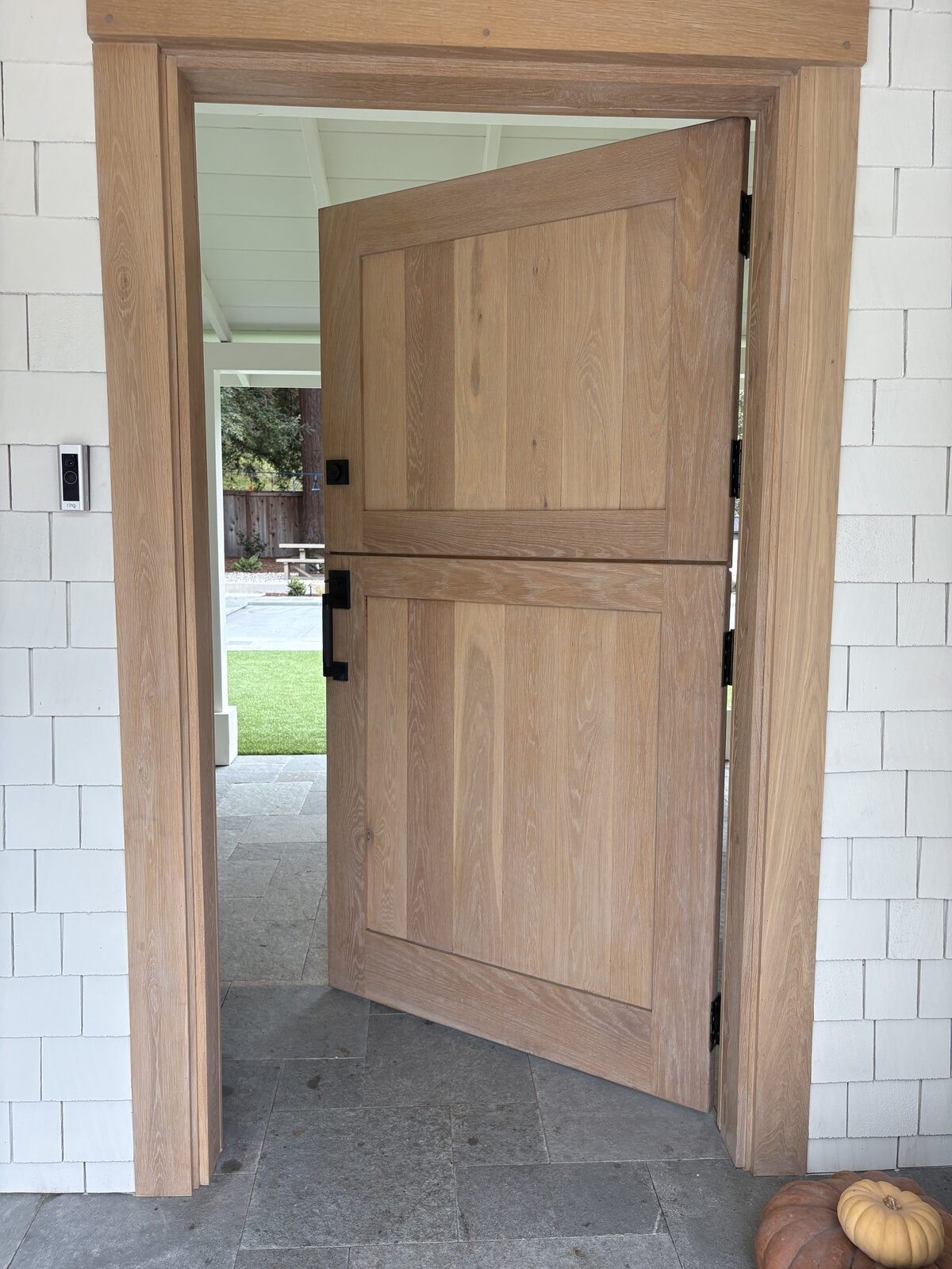 White oak Dutch-style swing entry door gate set in shingle siding with stone threshold