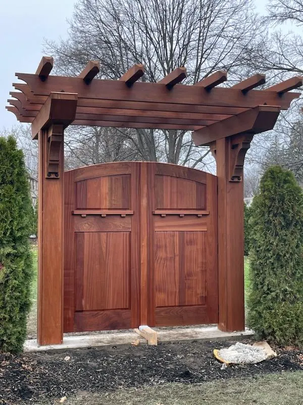 Double swing mahogany gate under a heavy timber pergola arbor