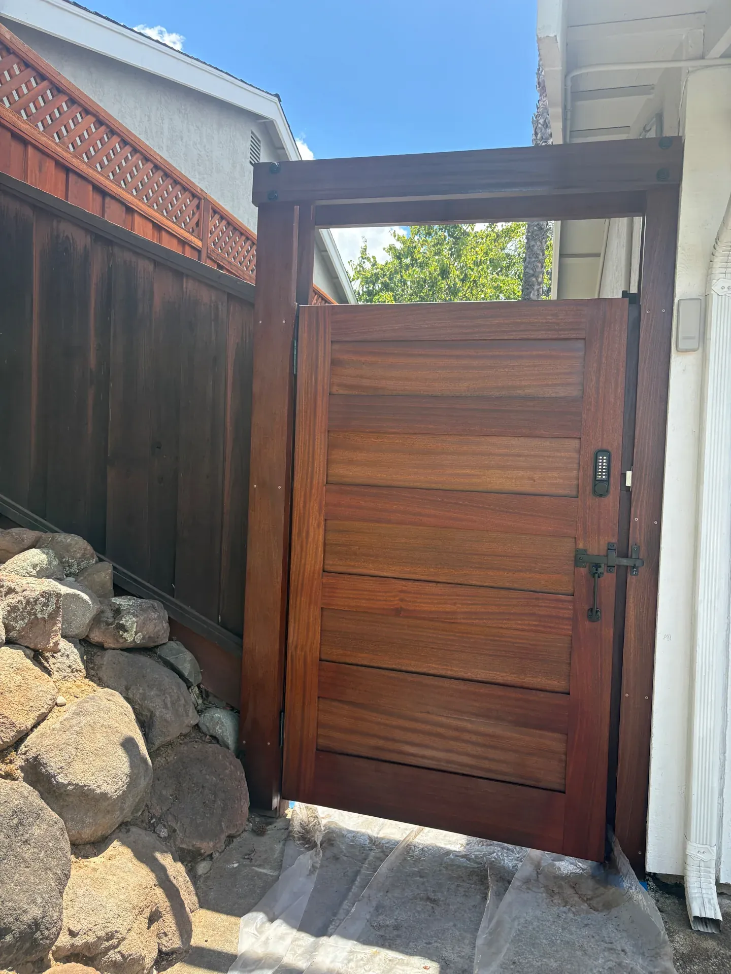 Tall sapele horizontal slat side-yard gate with smart keypad and steel strap hinges